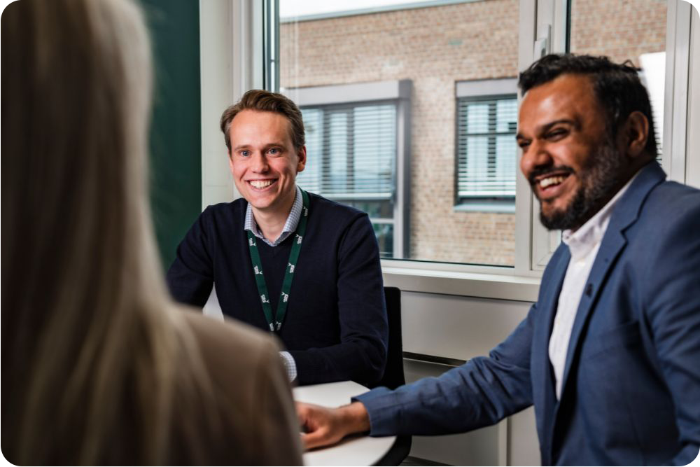 Tre kollegaer i møterom som smiler